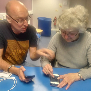 Volunteer helping an older lady with her smartphone